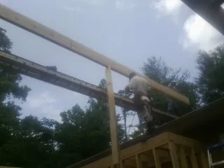 Carpenter setting a ridge beam over a new addition frame — Ice Dam Removal by Roofing Brothers in Point Harbor