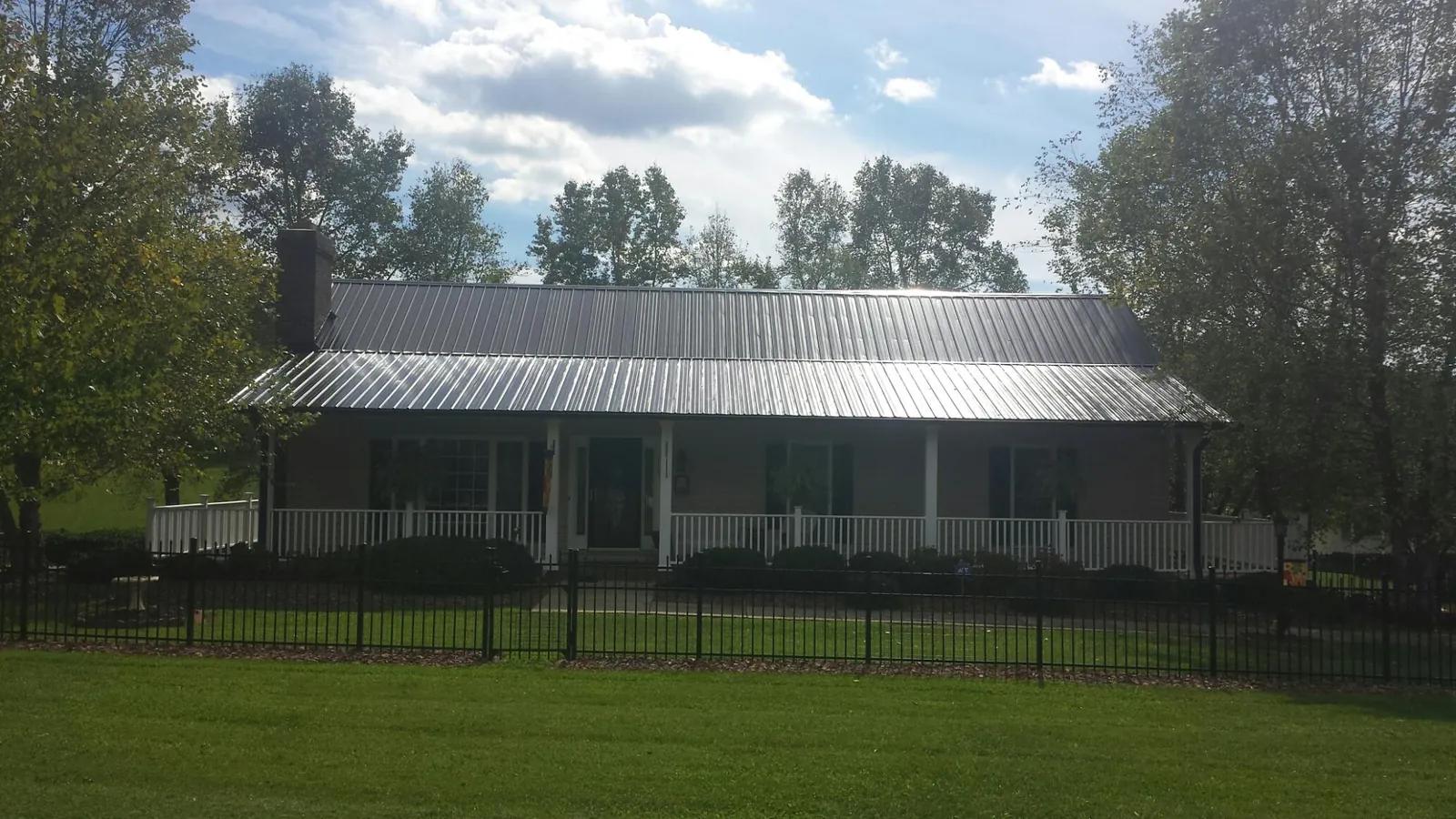 Gray metal roof on a brick ranch with a full width front porch — Gutter Guard Installation work by our crew in Point Harbor