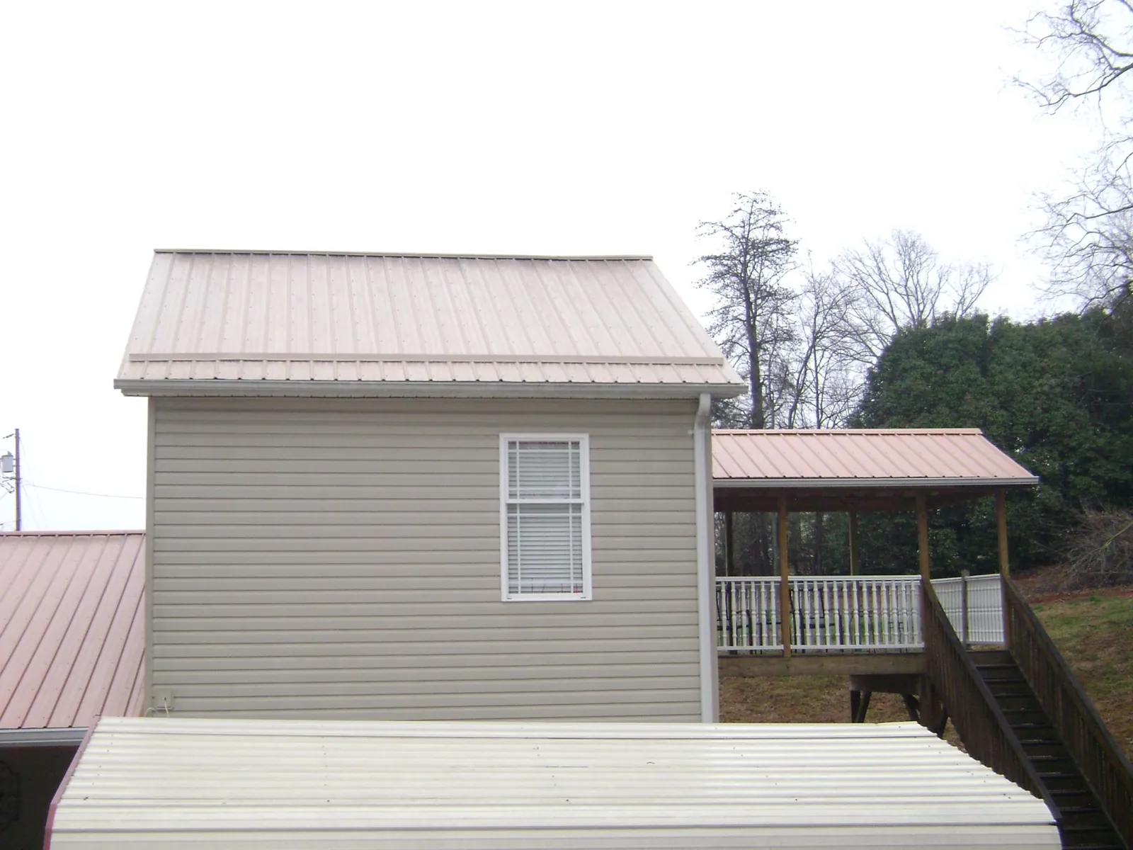Tan metal roofs on a two story addition and attached porch, from a Roof Replacement job in Point Harbor