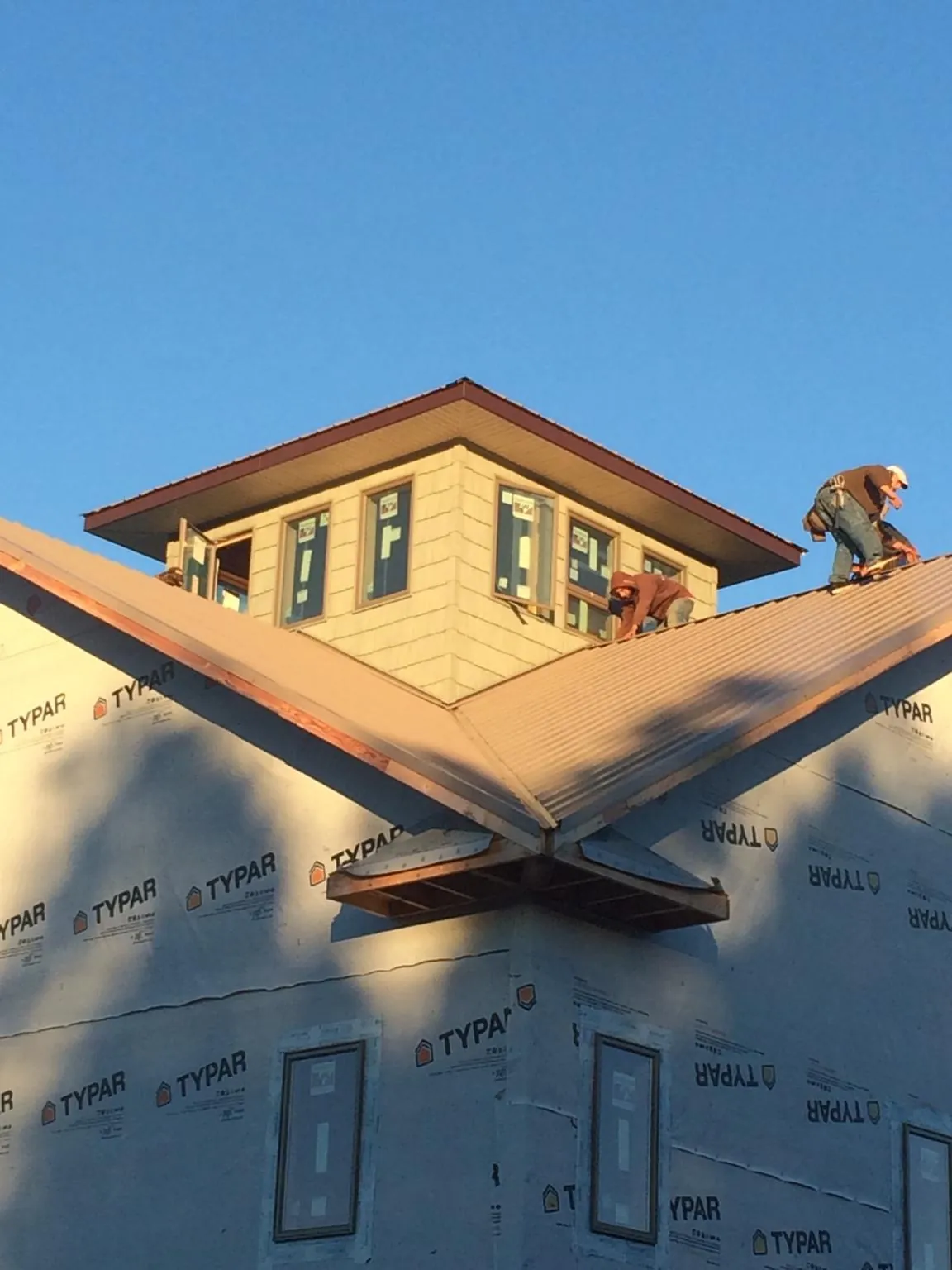 Roofers working around a rooftop cupola on a new metal roof at sunset — Roof Waterproofing in Point Harbor by Roofing Brothers